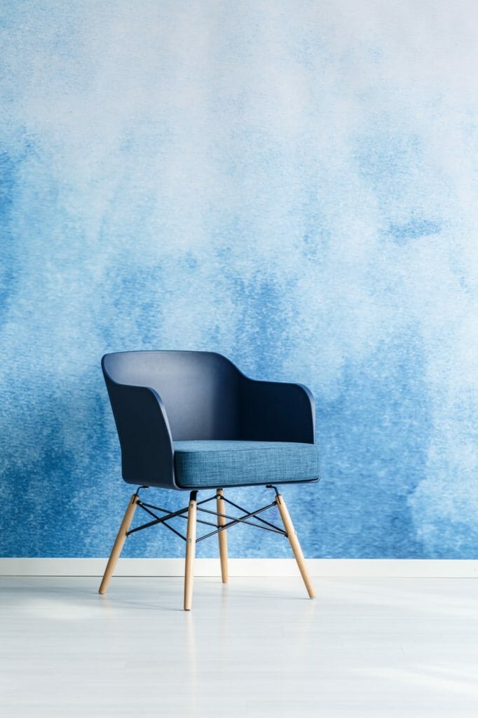 Single modern navy blue chair standing against empty blue and wh